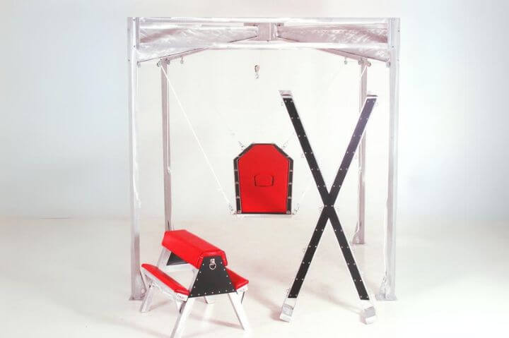 A red bondage horse next to an aluminum cross and red sex swing.